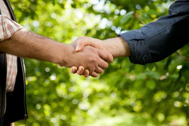 Händeschütteln zwischen zwei Personen, symbolisiert Partnerschaft im Agrarrecht.
