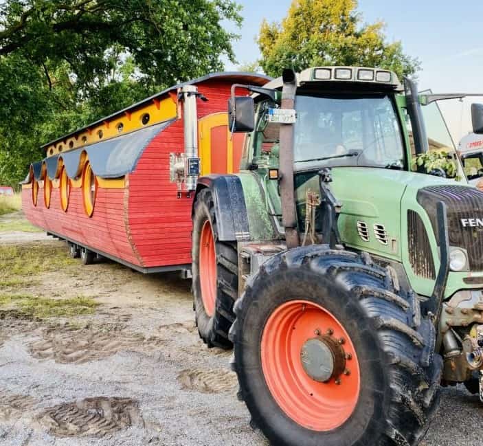 Alt: Traktor zieht bunten Floß, ideal für landwirtschaftliche und maritime Events.